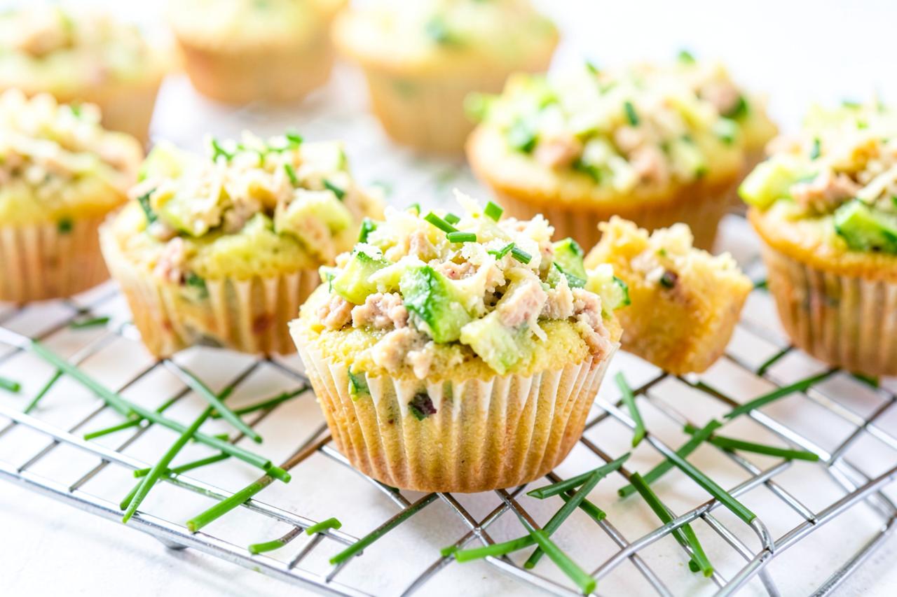 Muffins salés dorés au thon et à la courgette démoulés sur une grille avec de la ciboulette fraîche